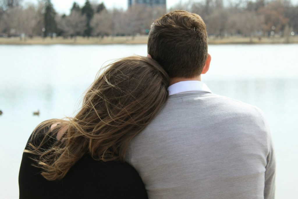 Femme posant la tête sur l’épaule de son compagnon, face à un lac